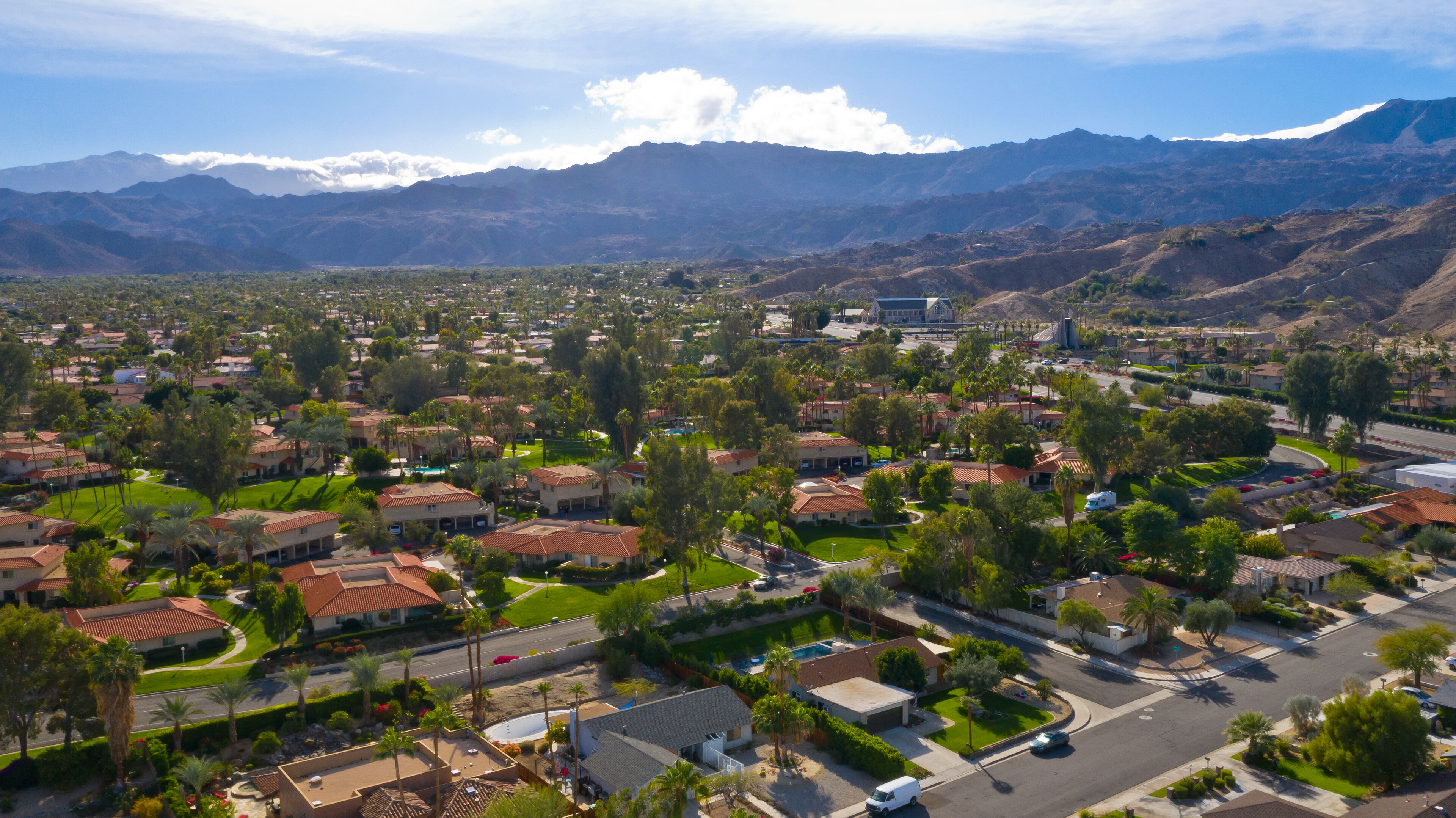 A residential area with houses, roads, and mountains in the background.