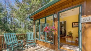Une terrasse en bois avec des fauteuils à bascule et une jardinière suspendue.