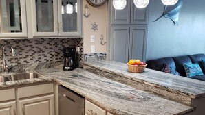 A modern kitchen with a granite countertop, stainless steel appliances, and a clock on the wall. - FUN VACATION GETAWAY (South Padre Island)