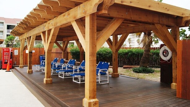 A wooden deck with blue lounge chairs, a lifebuoy, and a Coca-Cola vending machine. - FUN VACATION GETAWAY (South Padre Island)
