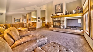 A spacious living room with a large sectional sofa, a fireplace, and a television.