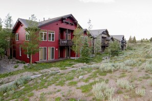 Ein rotes, zweistöckiges Haus mit Balkon, eingebettet in eine natürliche Landschaft mit Bäumen und einem Feldweg.
