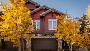 A two-story house with a stone foundation, a brown garage door, and a red exterior.