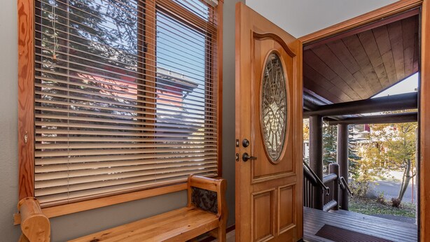 A wooden door with a glass panel, a bench, and a staircase leading to a covered porch.
