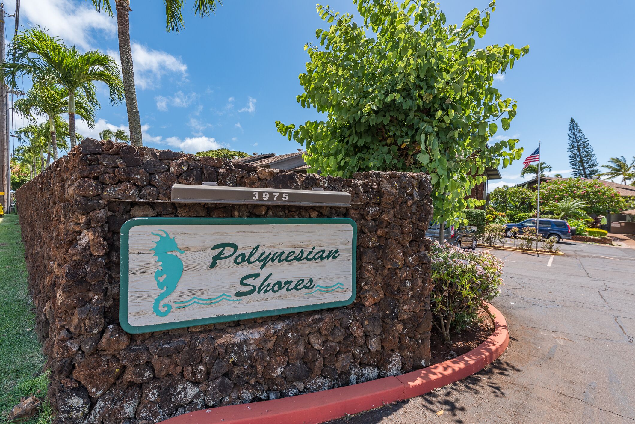 A sign for Polynesian Shores with a stone wall and a seahorse logo.