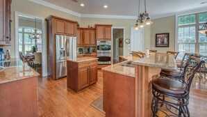 A spacious kitchen with wooden cabinets, stainless steel appliances, and a large island with bar stools.