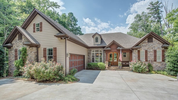 A two-story house with a stone facade, a front porch, and a garage.