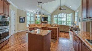A spacious kitchen with a large island, wooden cabinets, and a ceiling fan.