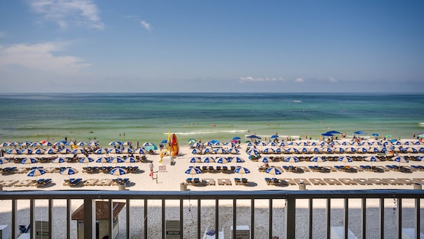 A beach with rows of sun loungers and umbrellas, a lifeguard tower, and the ocean in the background. - Spectacular -  Beach front condo from 149 night - no extra administrative fees. (Panama City Beach)