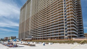 A high-rise hotel with multiple balconies, a beachside location, and a sandy beach area with sun loungers. - Spectacular -  Beach front condo from 149 night - no extra administrative fees. (Panama City Beach)
