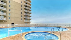 A swimming pool with a hot tub, surrounded by a brick deck, and a high-rise building with balconies in the background. - Spectacular -  Beach front condo from 149 night - no extra administrative fees. (Panama City Beach)