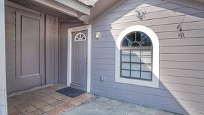 Une maison à l’extérieur gris, avec une porte d’entrée dotée d’une fenêtre en demi-lune et un petit porche.