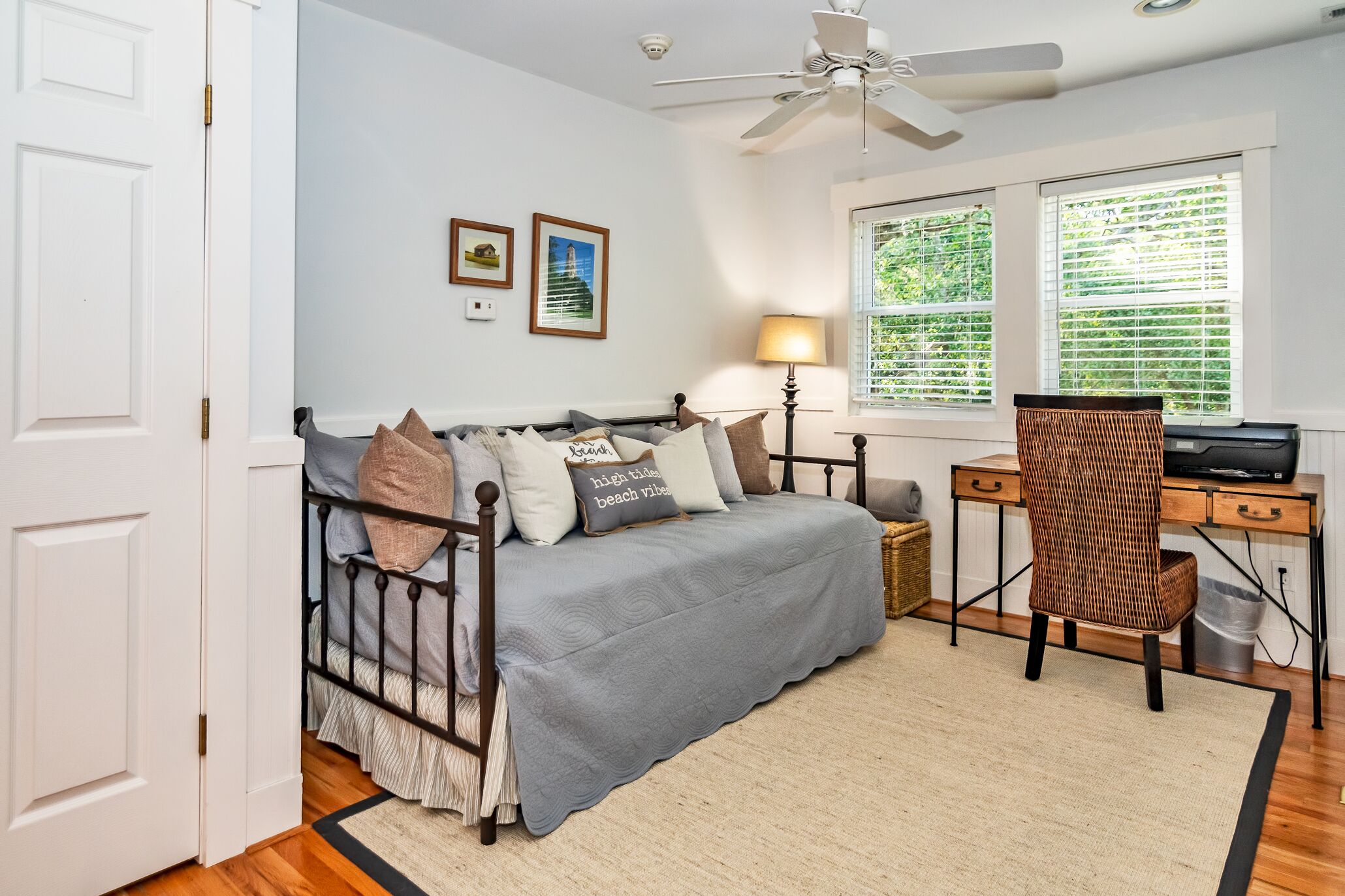 A bedroom with a bed, a desk, a chair, a lamp, and a ceiling fan.
