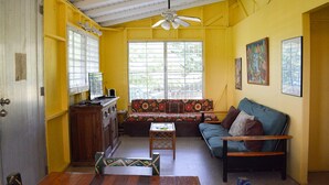 A room with a wooden ceiling, a sofa, a small table, and a window with blinds.