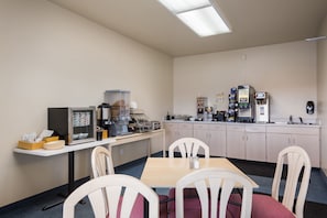 A small, clean room with a kitchenette, a table, and four chairs.