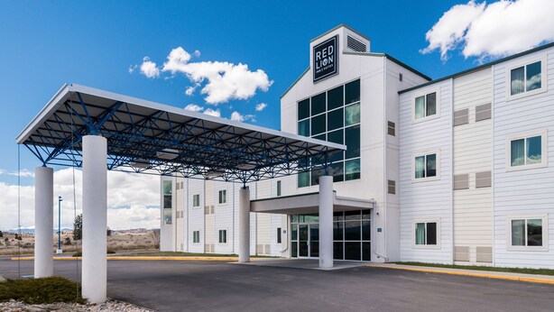 A modern hotel entrance with a covered walkway, large windows, and a prominent sign. - Red Lion Inn & Suites Butte (Butte)