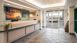 A hotel reception area with a reception desk, a large poster, and a view through the glass doors. - Red Lion Inn & Suites Butte (Butte)