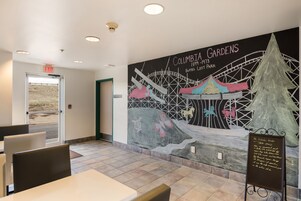 Un restaurante con un mural de Columbia Gardens, un letrero y una pizarra con el menú.