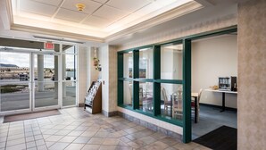A hotel lobby with a tiled floor, an exit sign, a reception desk, and a view of the outside. - Red Lion Inn & Suites Butte (Butte)
