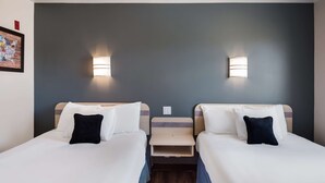 A hotel room with two beds, each with white linens and a dark pillow. There are wall-mounted lights on either side of the beds. - Red Lion Inn & Suites Butte (Butte)