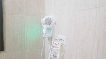 A white telephone mounted on a wall with a corded handset.