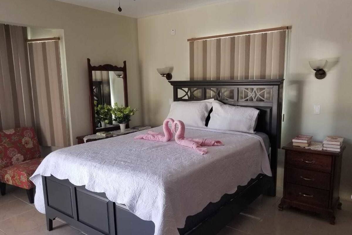 A bedroom with a bed, a nightstand, a chair, and a mirror.