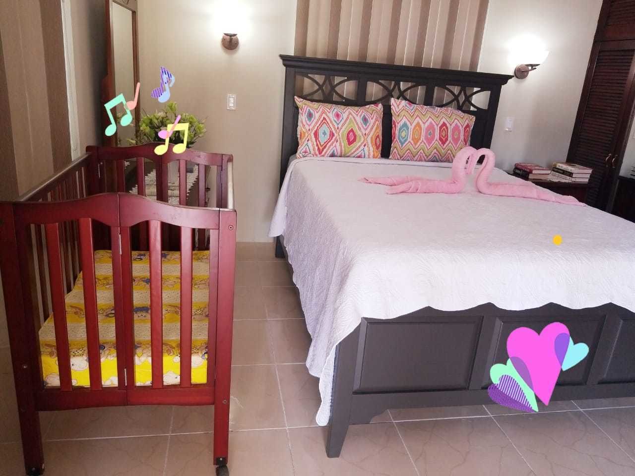 A bedroom with a bed, a crib, and a nightstand.
