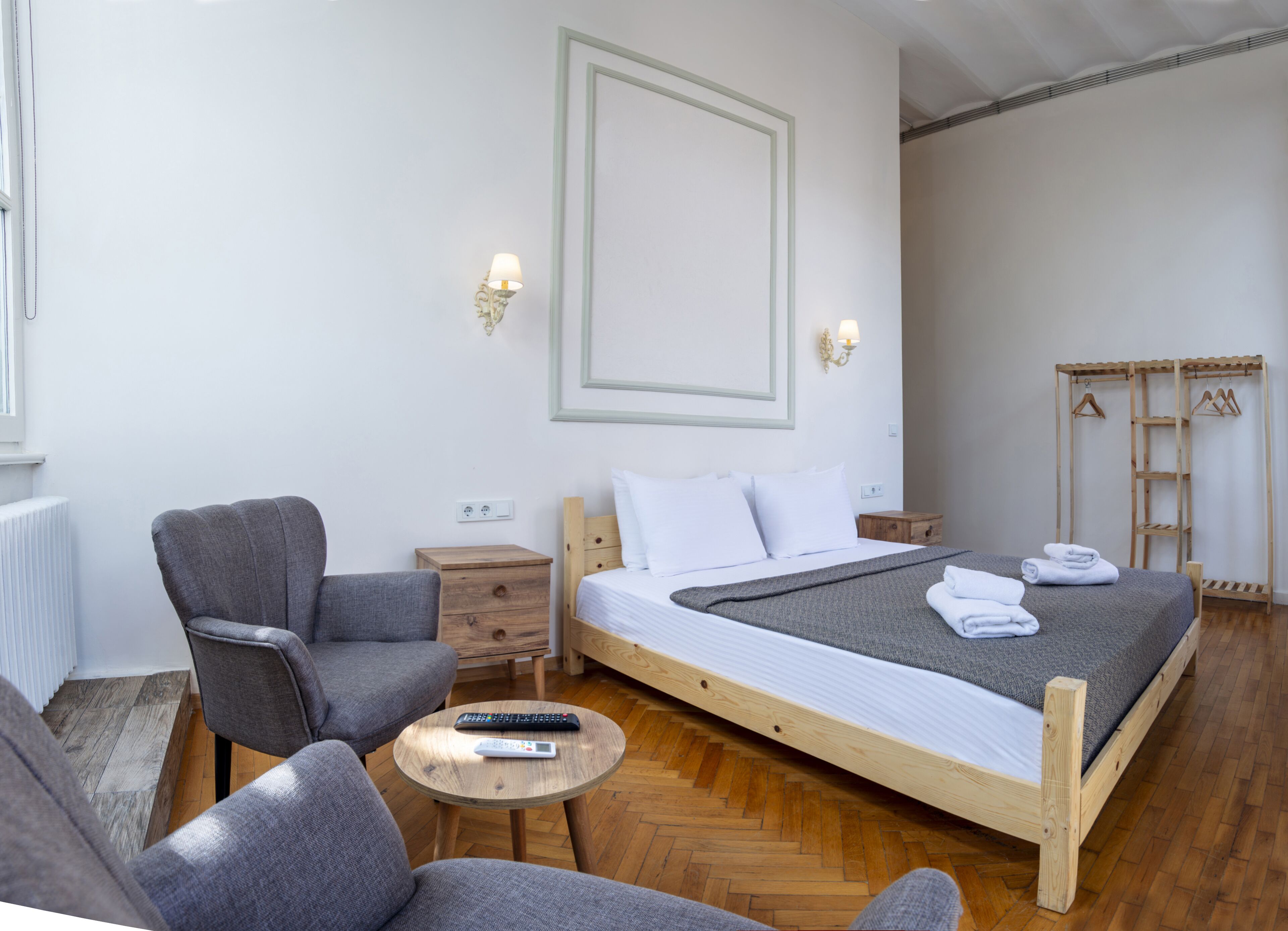 Quarto com uma cama, uma cadeira, uma mesinha e um guarda-roupa de madeira.