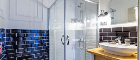 A modern bathroom with a glass-enclosed shower, a white toilet, and a sink with a mirror above it.