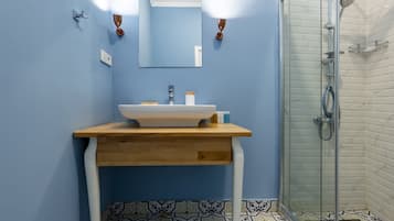 A bathroom with a sink, mirror, and shower.