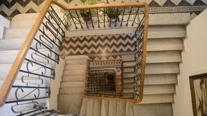 A staircase with a geometric patterned wall, a metal handrail, and a small enclosed area with a patterned floor. - Cezayir Rooms (Istanbul)