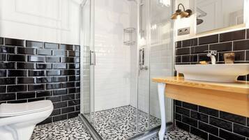 A bathroom with a glass-enclosed shower, a white toilet, and a sink with a wooden countertop.