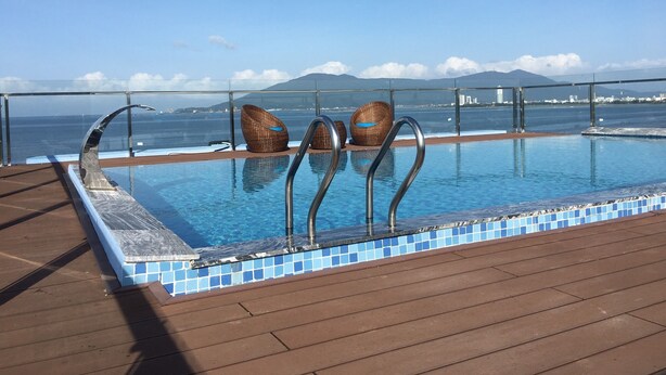 Ein Pool mit freiem Blick auf das Meer und die dahinterliegenden Berge.