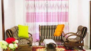 A room with a sofa, two chairs, a small table, and a decorative vase with flowers. - Family Ties GUEST INN (Bandarawela)