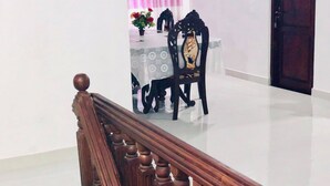 A staircase with wooden balusters leading to a dining area with a table and chairs. - Family Ties GUEST INN (Bandarawela)