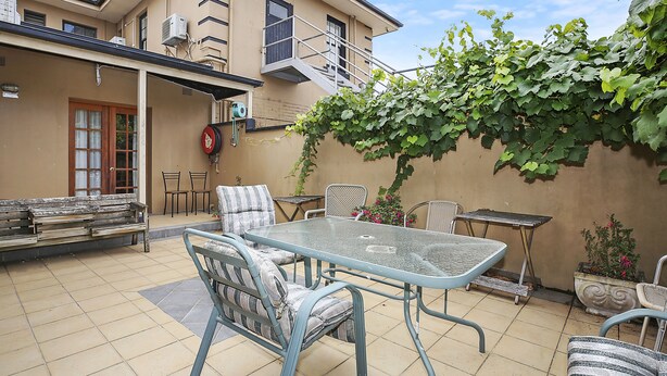 A patio with a glass table and chairs, a bench, and a potted plant. - Grand Central Accommodation B&B Cobden (Cobden)