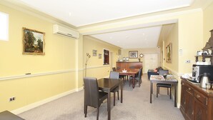 A dining area with a wooden table and chairs, a kitchen area with a coffee machine, and a hallway with framed pictures on the walls. - Grand Central Accommodation B&B Cobden (Cobden)