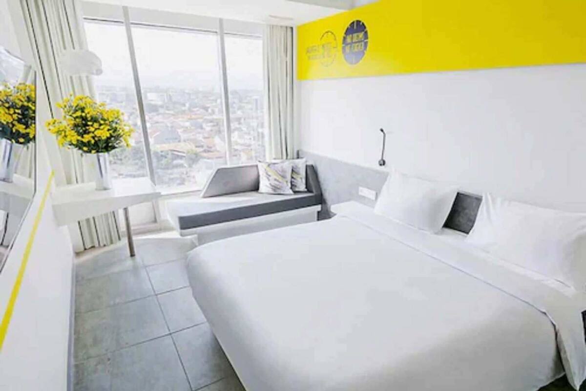 A hotel room with a large bed, a desk, and a view of the city.