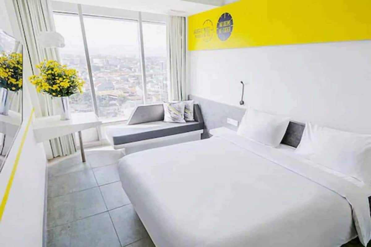 A hotel room with a large bed, a desk, and a view of the city.