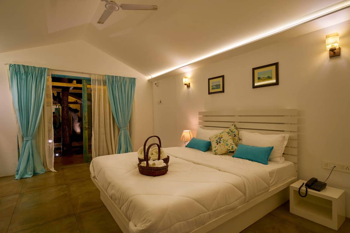 A hotel room with a large bed, a bedside table with a phone, and a wall-mounted light.