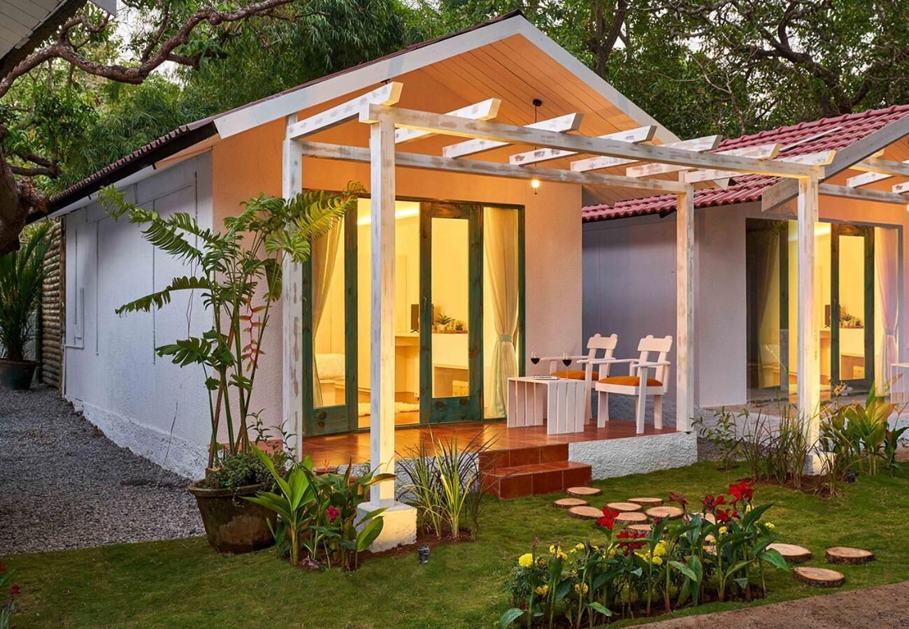 A cozy, single-story house with a covered porch, a small garden, and a seating area with a table and chairs.