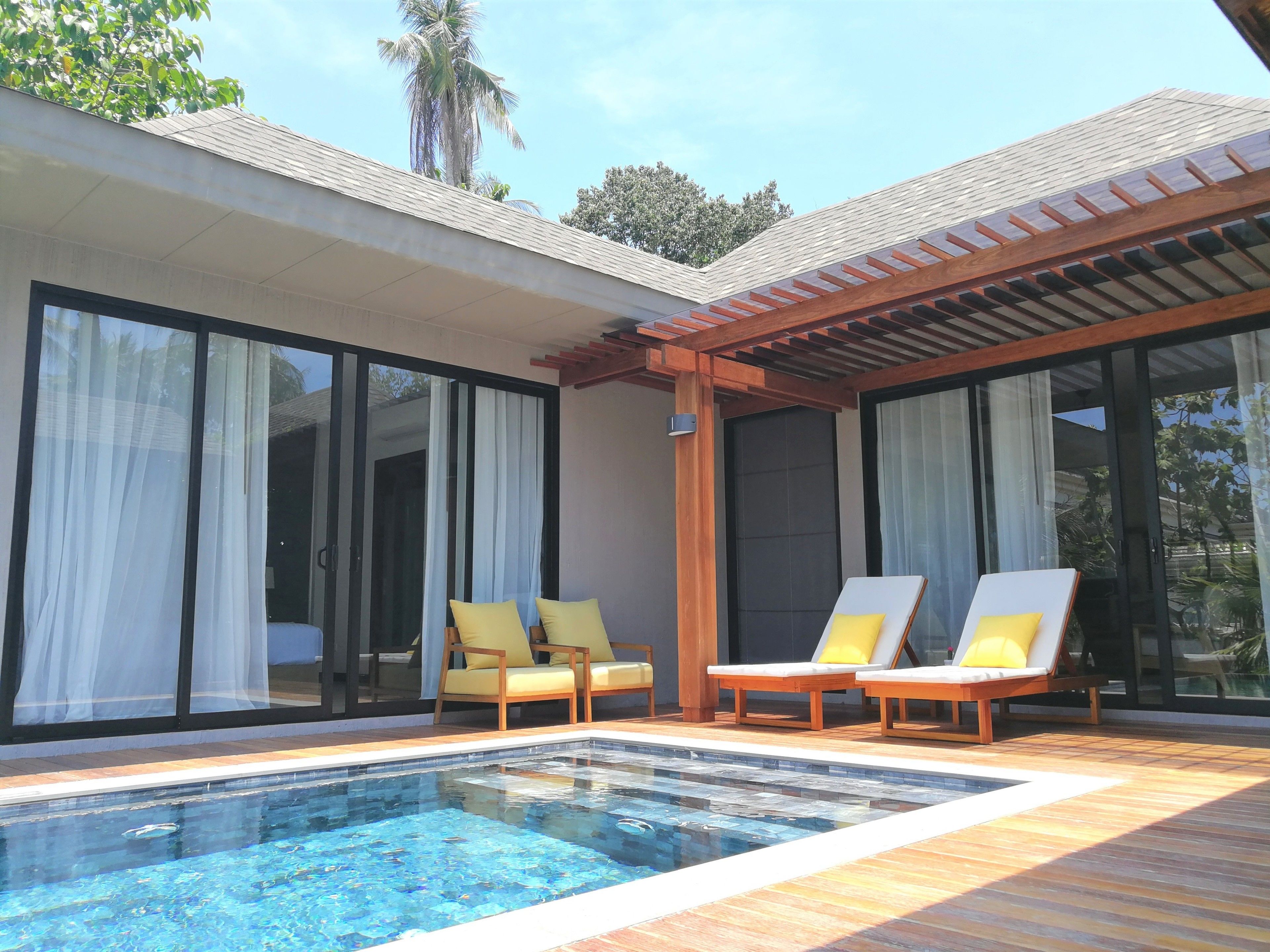 Ein Poolbereich mit zwei Liegestühlen und einer Pergola.