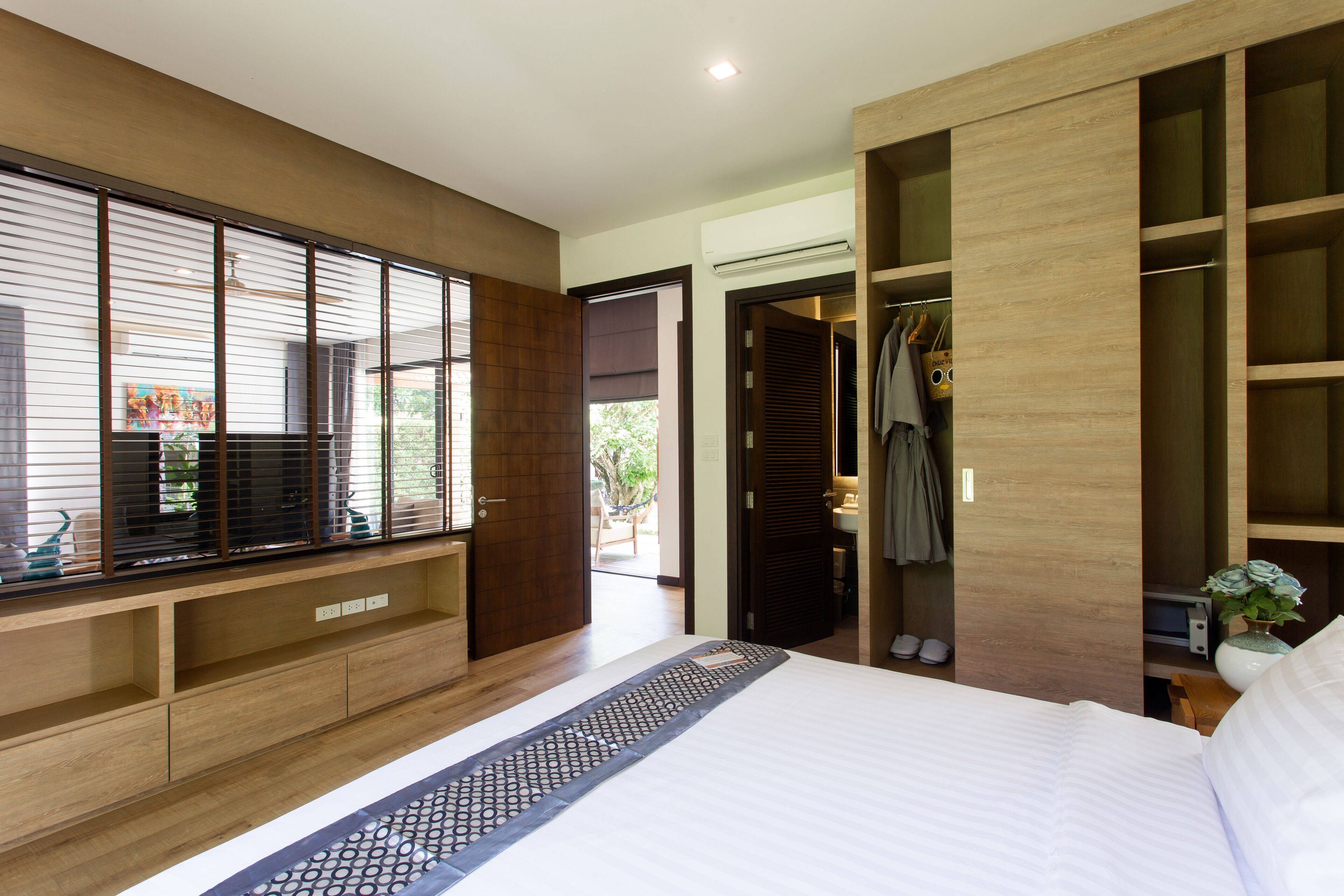 Una habitación de hotel moderna con una cama grande, armario empotrado y un área de descanso con vistas al exterior.