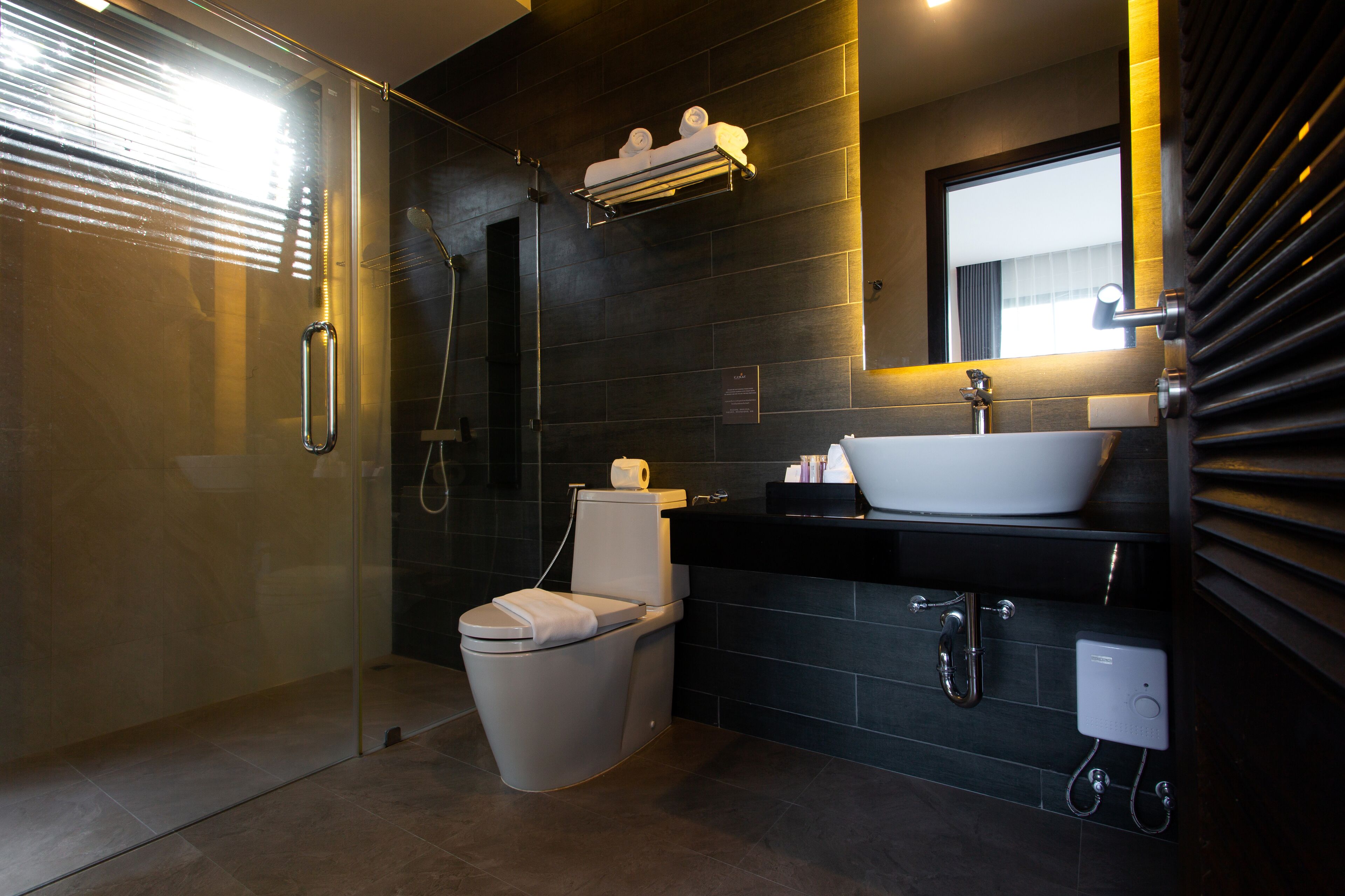 Un baño moderno con cabina de ducha de vidrio, inodoro, lavabo con espejo y toallero.