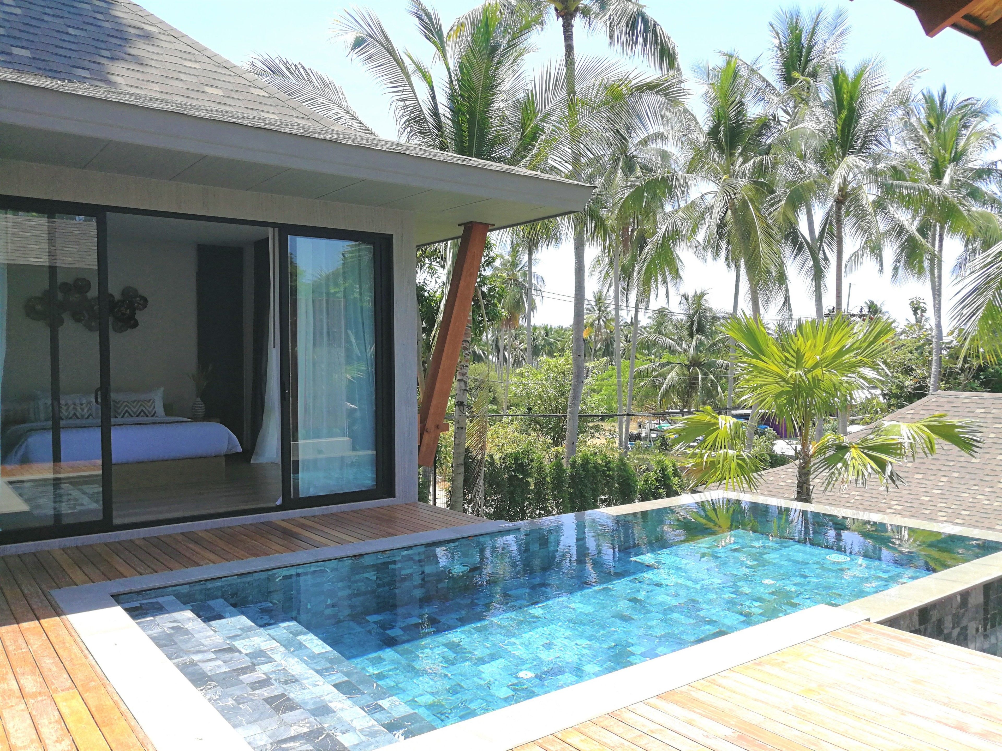 A modern villa with a glass-enclosed bedroom, a wooden deck, and a swimming pool.