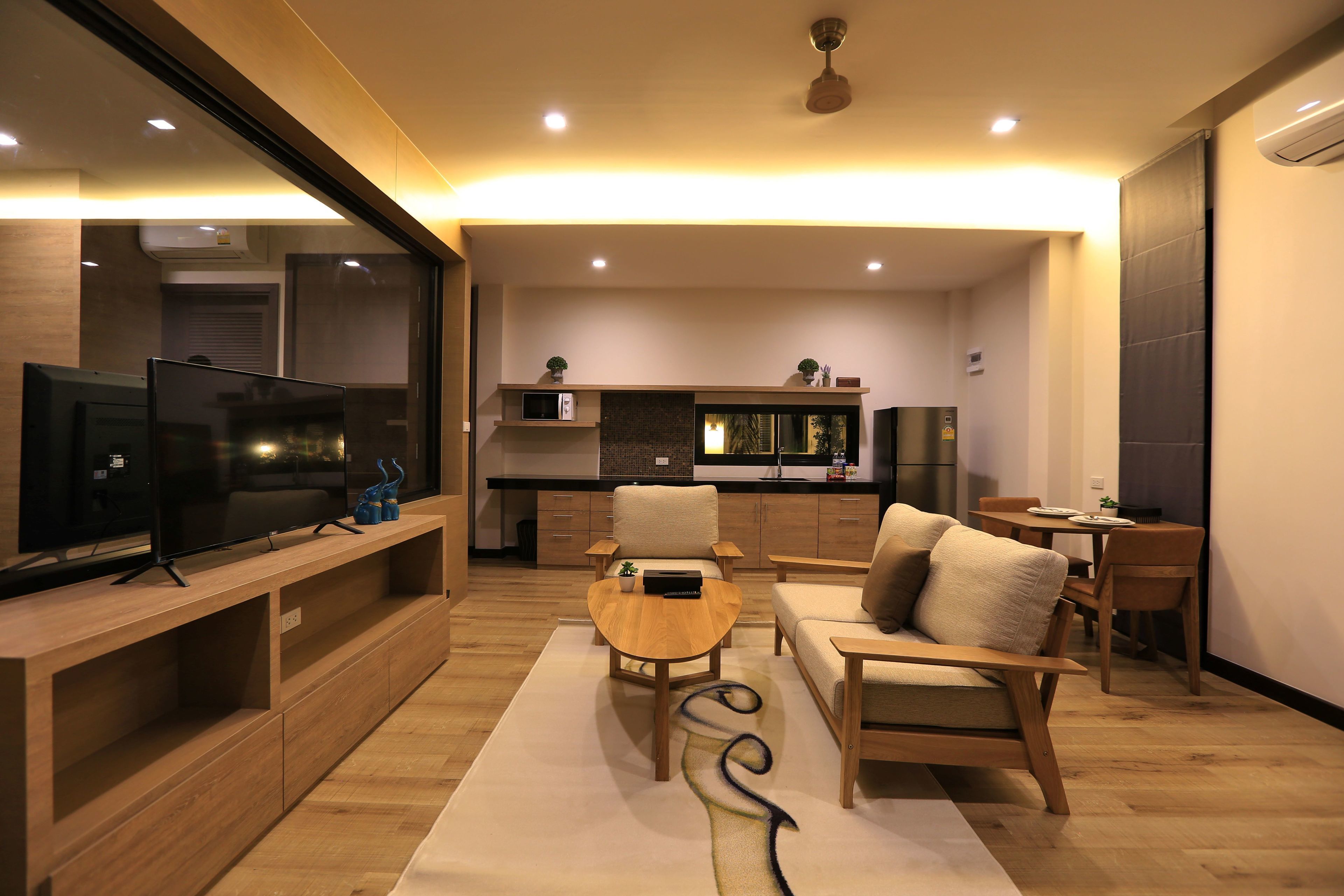 A modern living room with a TV, wooden furniture, a kitchen area, and a dining table.