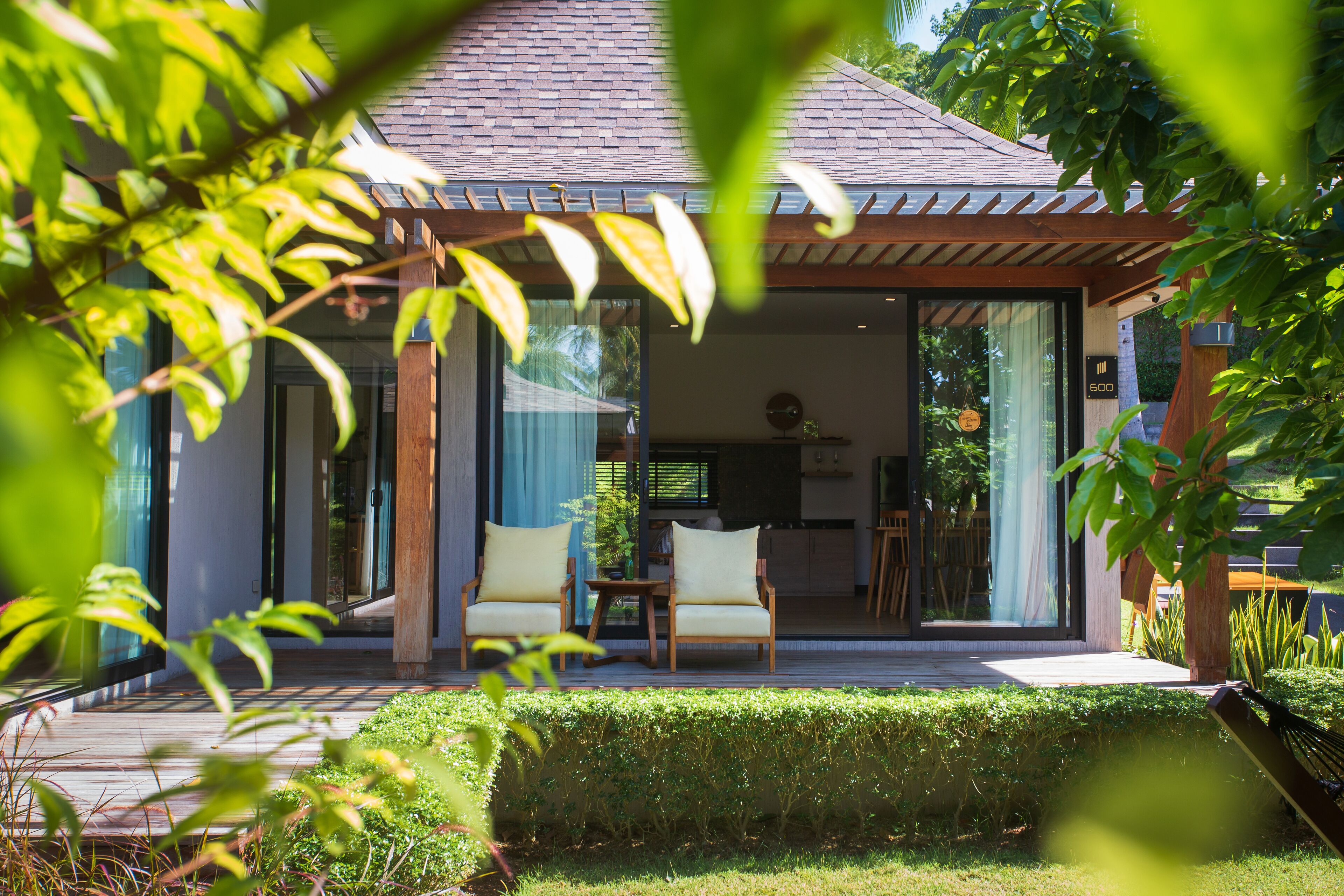Una casa moderna con un porche cubierto, dos sillas y una mesa.