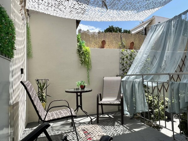 Een terras met twee stoelen, een tafeltje en een hangplant.