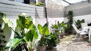 Un espace patio agrémenté de plantes en pot, d’une chaise blanche et d’une table.