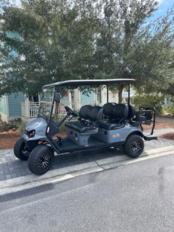 A golf cart parked on a paved driveway.